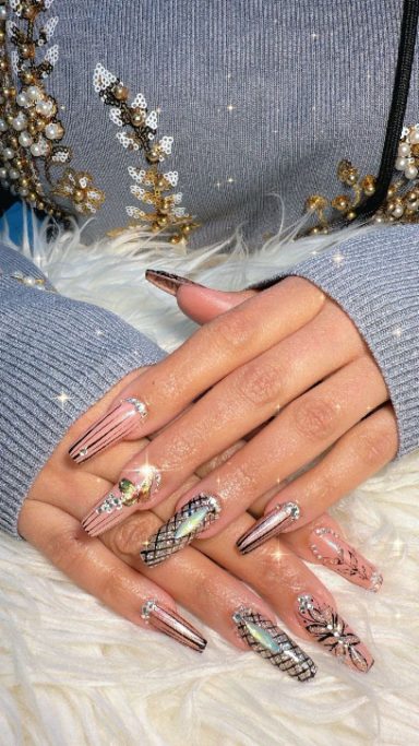 Gelaakte nagels met glinsterende en holografische ontwerpen op een zachte achtergrond.