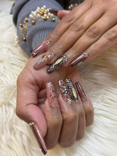 Gepolijste nagels met decoratieve designs en glitters op een zachte ondergrond.