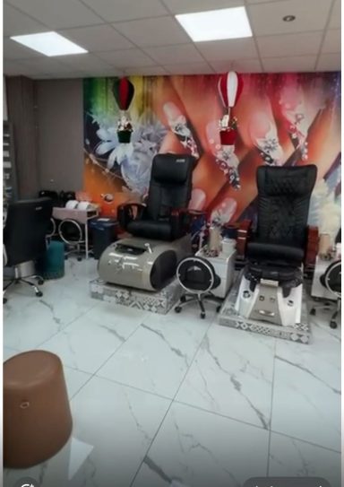 Moderne nagelstudio met twee zwarte pedicure stoelen en kleurrijke muurdecoratie.