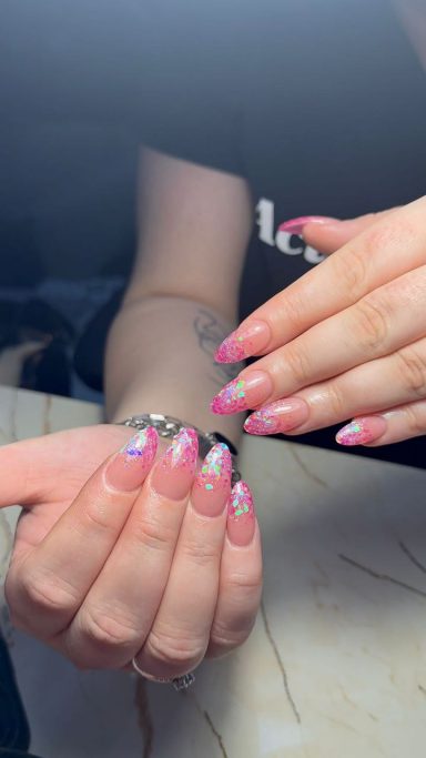 Handen met roze nagels, decoraties en een lichte Franse manicure.