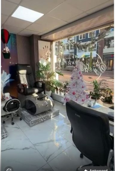 Een moderne behandelruimte met een massagestoel en planten, uitzicht op de straat.