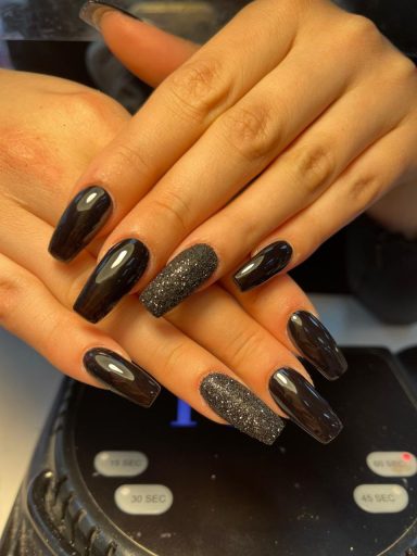Zwart gelakte nagels met sprankelende accenten, lange vorm, en fraaie afwerking.