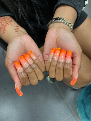 Felgekleurde nagels in een ombre-effect van oranje naar transparant.