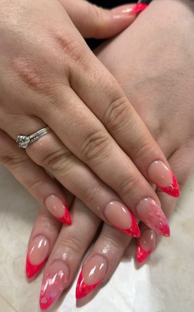 Lichtroze nagels met felle roze french tips en een ring op de vinger.