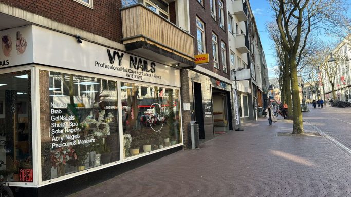 Voorkant van een winkel met ruime etalage en stedelijke straatomgeving.