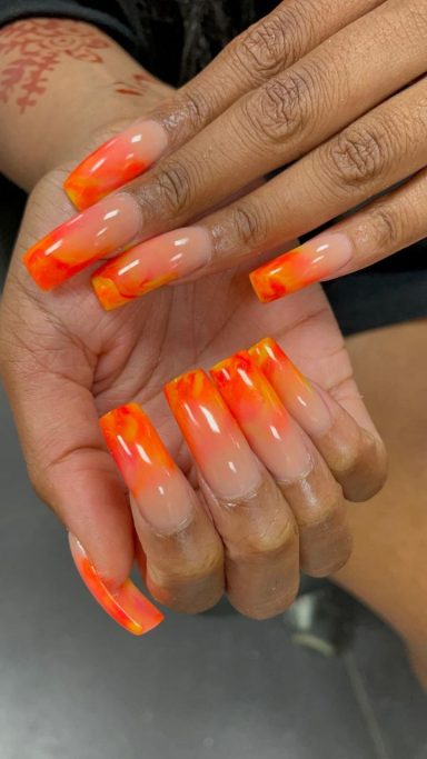 Vijf lange, ombre nagels in oranje tinten met een glanzende afwerking.